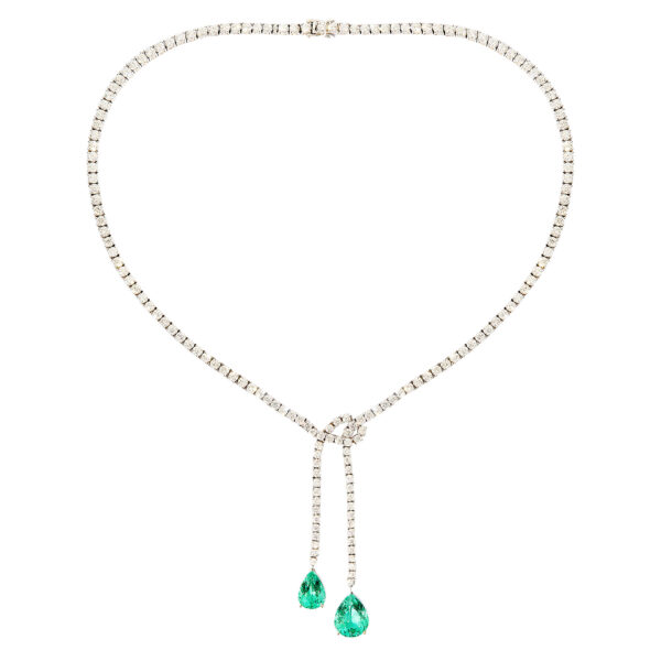 18k white gold rope necklace with diamond-set chain tied in a bow and two emerald drop pendants on a white background